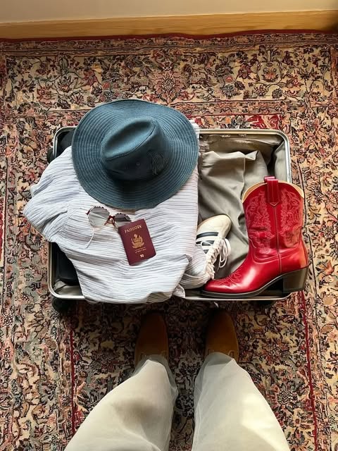 Kai vom Instagram-Feed: gepackter Koffer mit Hut und roten Stiefeln.