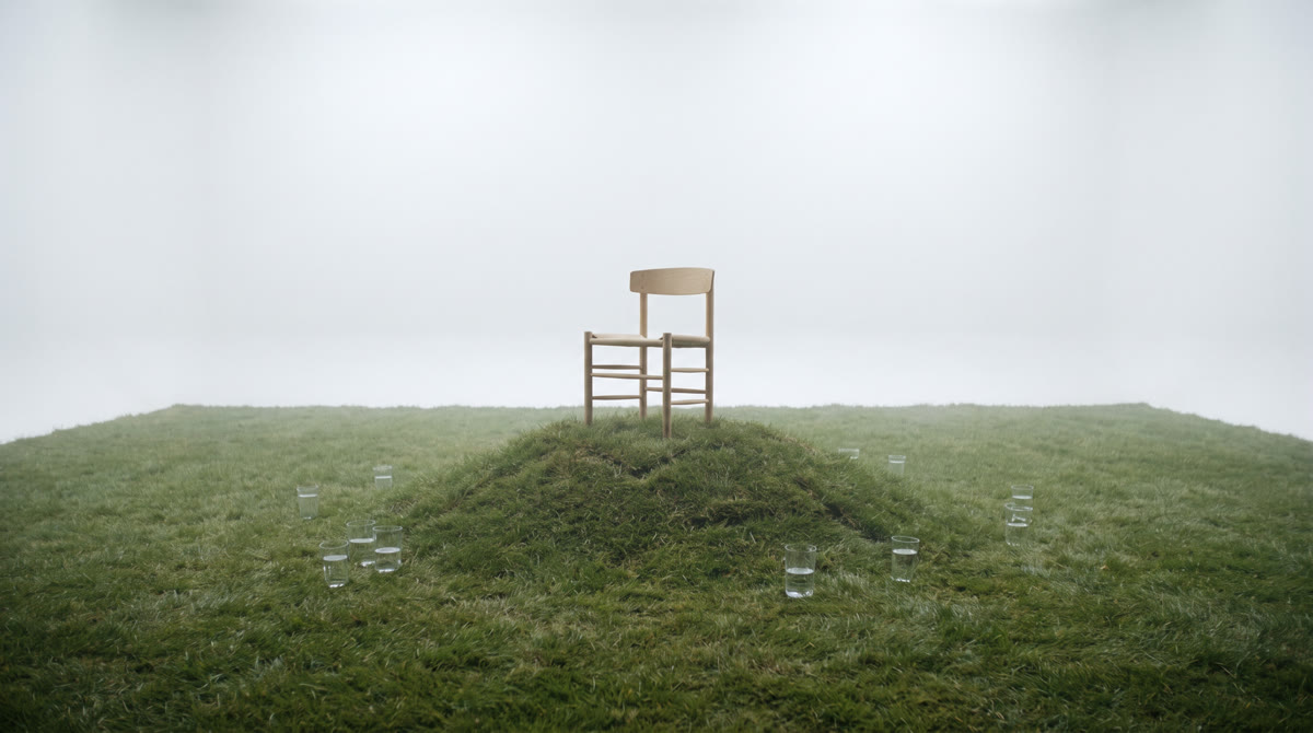 Referenzfoto: ein Stuhl auf einem grasbewachsenen Hügel, umgeben von Wassergläsern.
